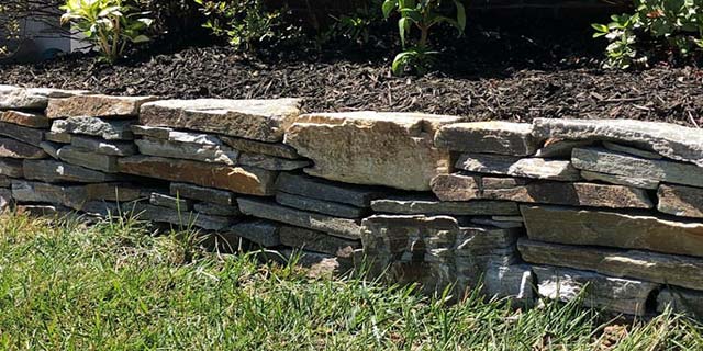 Natural stone retaining wall around a landscape bed in Middleburg, VA.